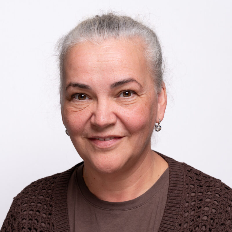 Woman with grey hair tied back and dark eyes