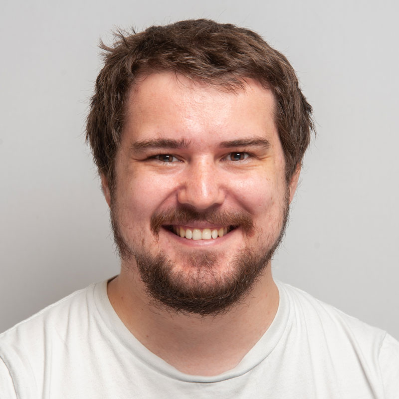 Image of a white man with medium brown, short hair, brown eyes and a brown goatee. He is wearing a white t-shirt.