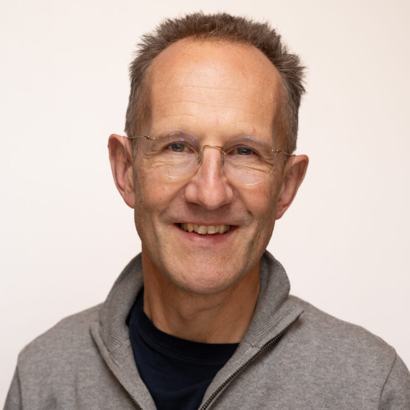 Man with short hair, wearing glasses with blue eyes.