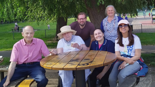 Image of a group of people who attended the Ruils wellbeing walk. They are seated around a circular table in the park.