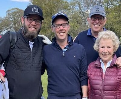 Three men and one woman participating in the Ruils golf day. They are standing on the course and holding their clubs.