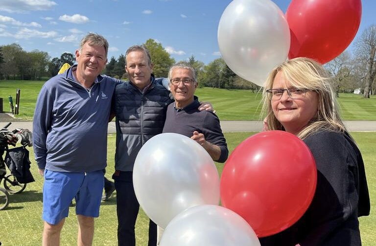 Four Ruils golf day participants standing out on the gold course. A woman is holding red and white balloons being used for the mulligans.