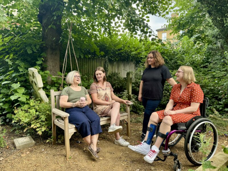 Four members of the Ruils team seated in a community garden having a chat.