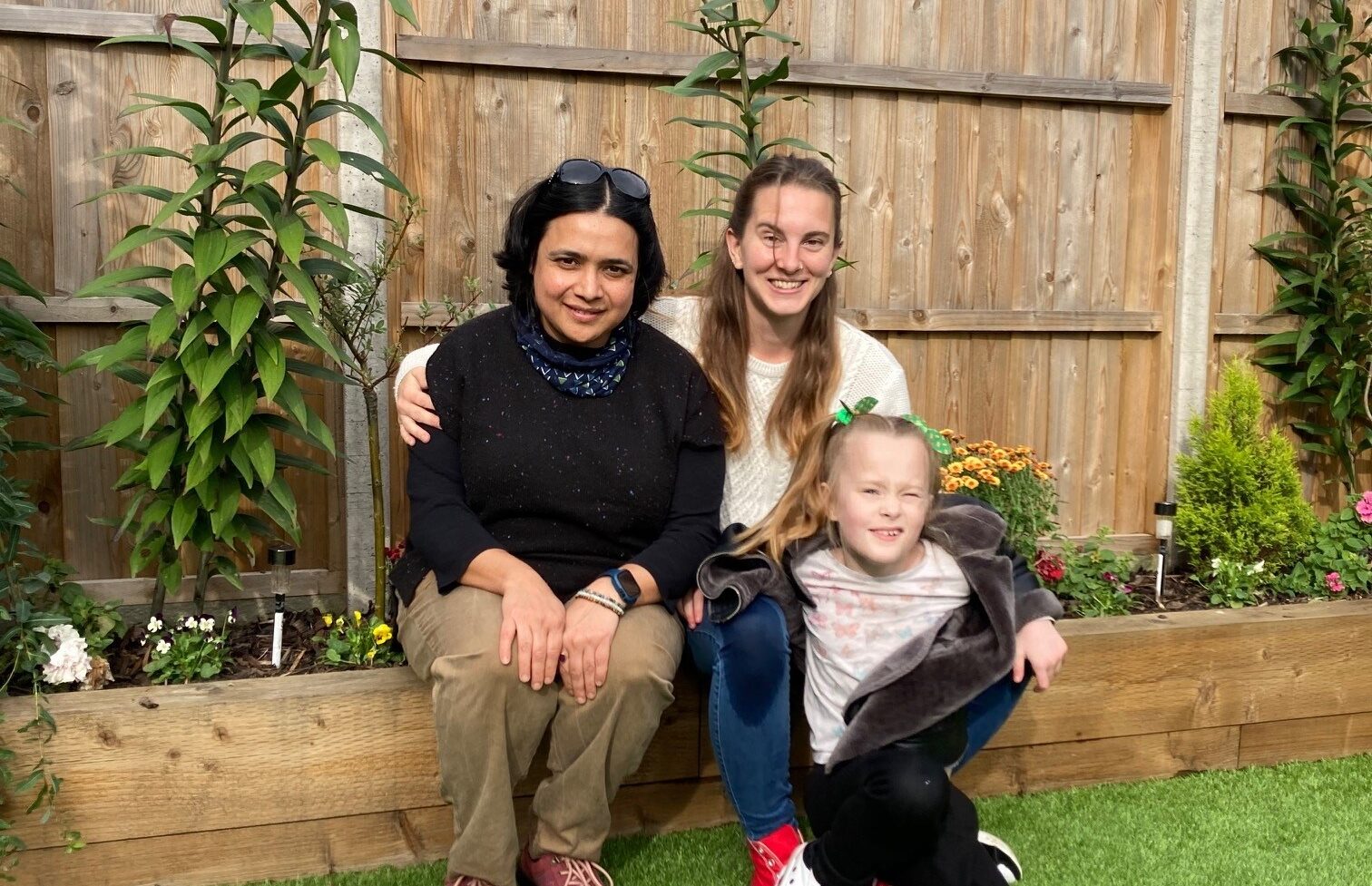 Parent Support Worker Surabhi sitting with client Jess and he daughter Laura. They are sitting in their front garden.