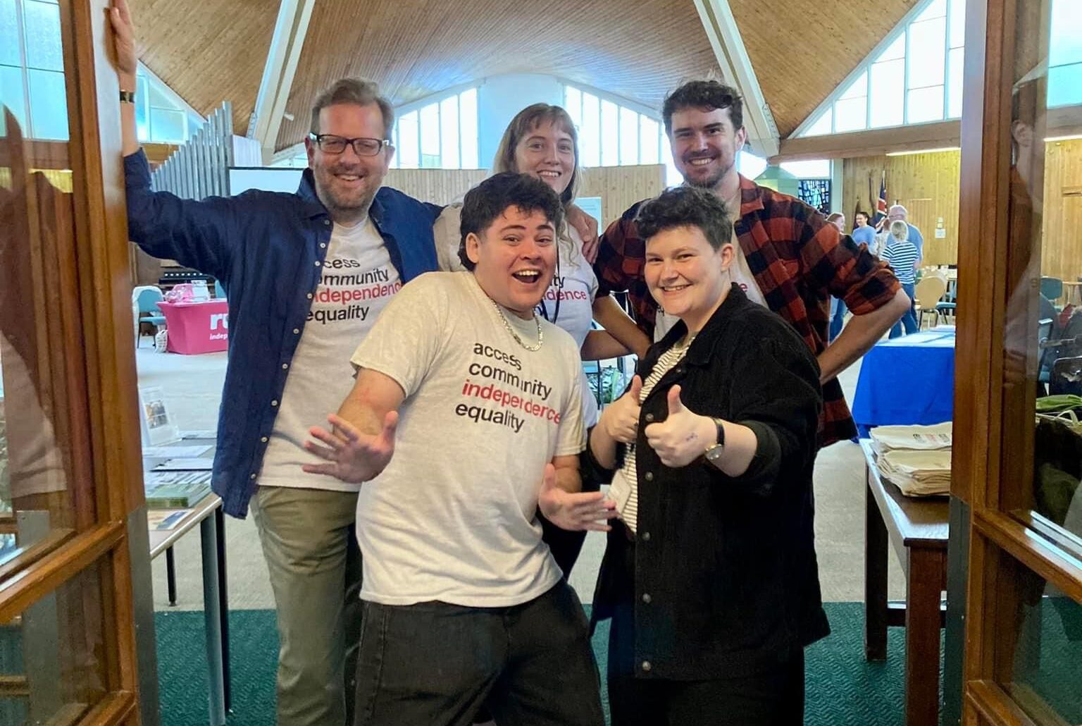 Group photo of the Ruils staff team supporting a health and wellbeing community event. They are wearing grey Ruils t-shirts and have big smiles and thumbs up.