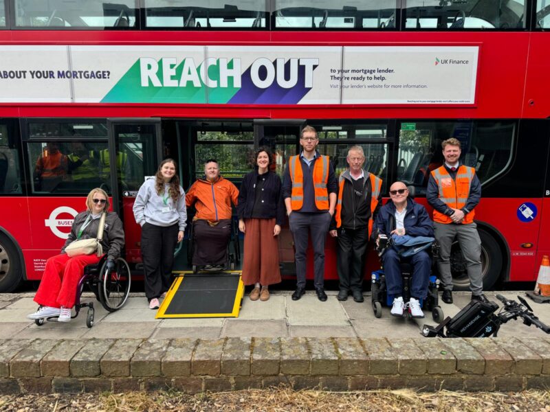 A group of people and stakeholders from RATP Dev and TfL sitting/standing in front of a red double decker bus.