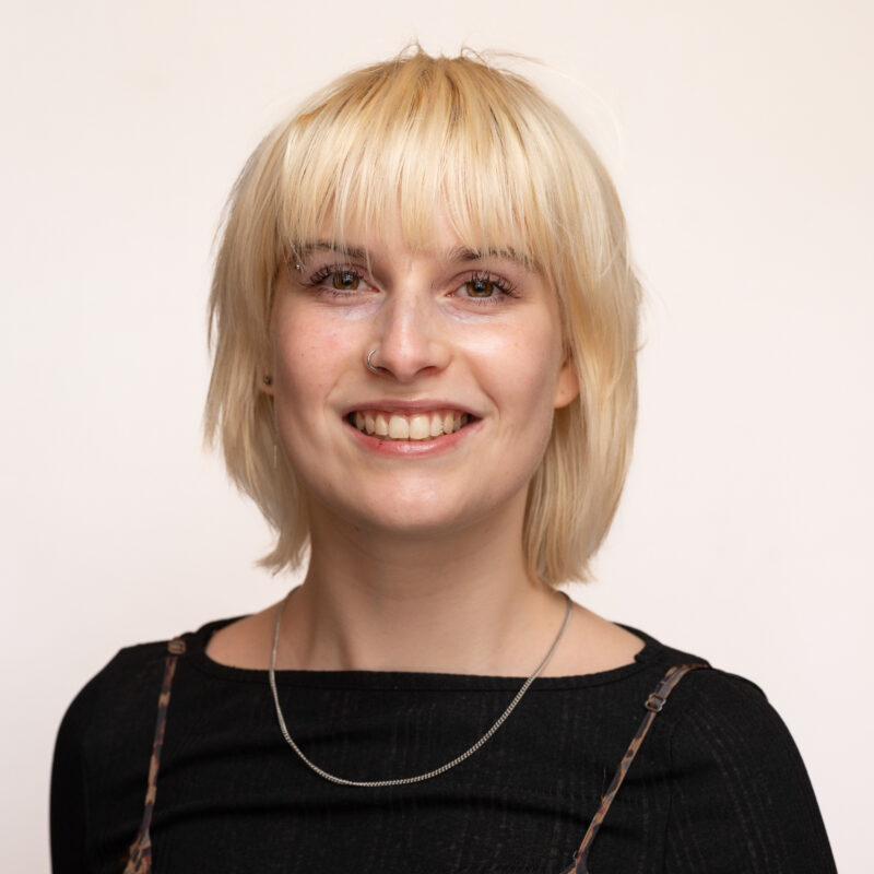 Woman with blonde shoulder length hair and a fringe with brown eyes