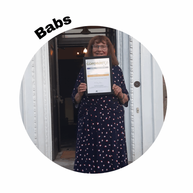 Image of Babs standing outside of a building holding up a certificate. Her name is above the photo in a circle frame.