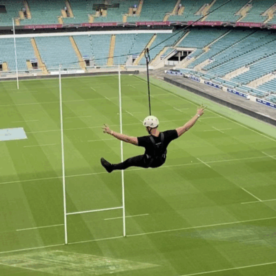 Image of a person wearing black zip-lining over a rugby pitch