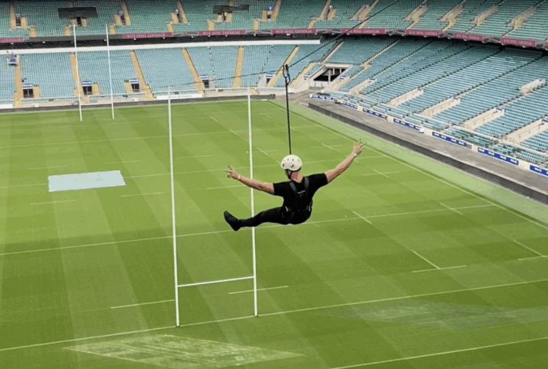 Image of a person wearing black zip-lining over a rugby pitch
