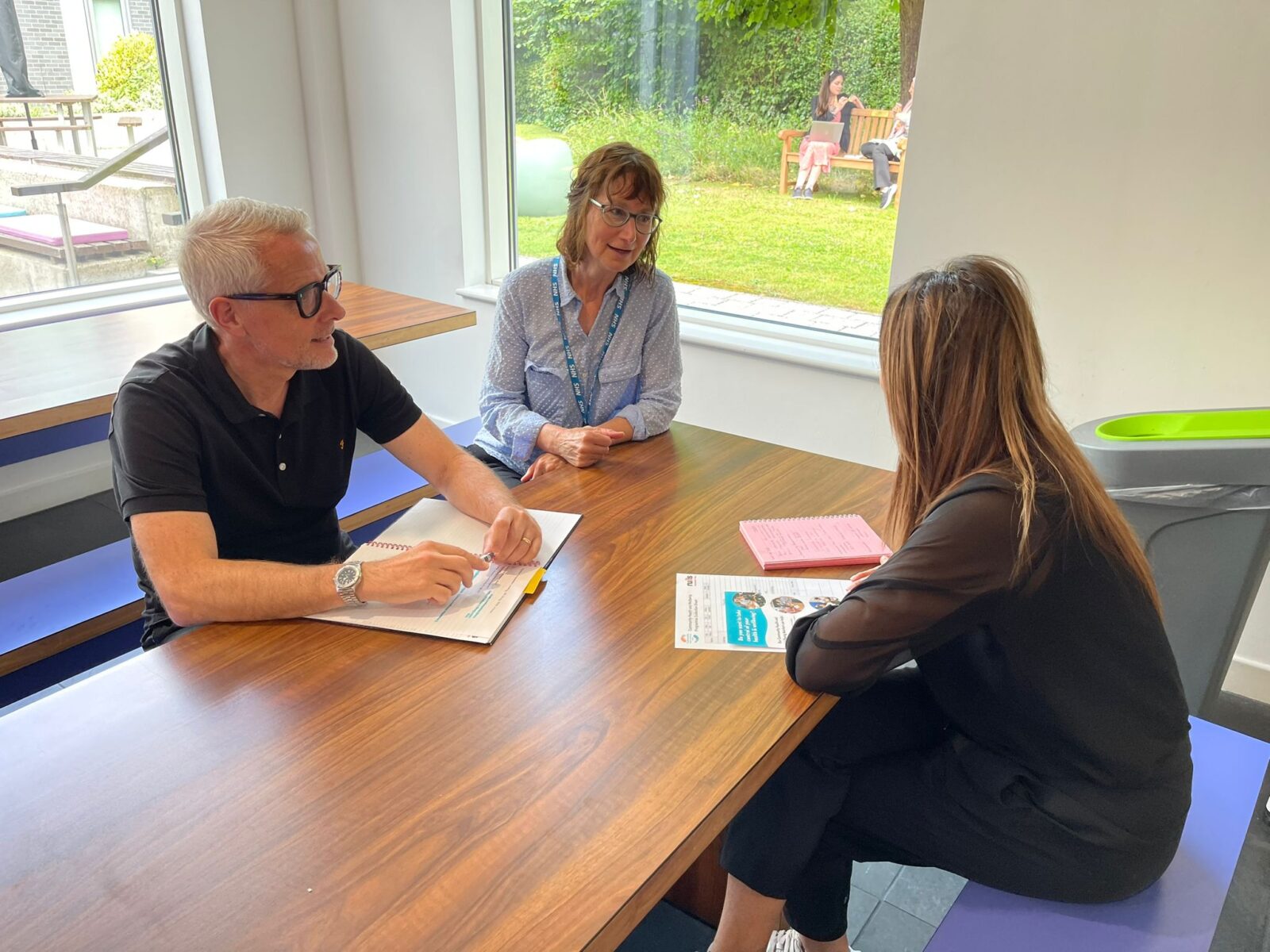 Image of three people sitting around a table having a discussion