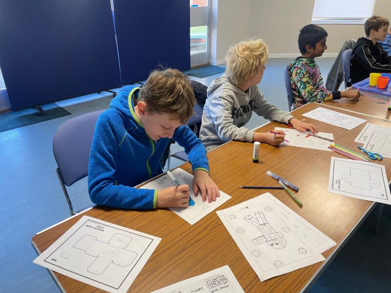 Image of three young boys sitting at a table crafting